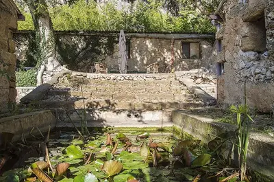 an old stone building with a pool of water and plants at Casa Portico, con piscina in comune in Terrasini
