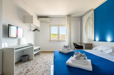 a bedroom with two beds and a blue wall at Centoquaranta Apartment in Terrasini