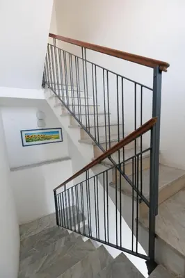 a stairway with a wooden rail and a stair case at Donna Rosalía Apartments in Trabia