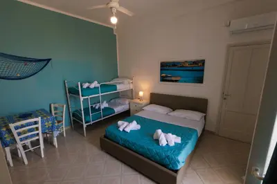 a bedroom with two beds and a table and chairs at Donna Rosalía Apartments in Trabia