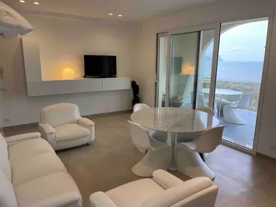 a living room with a table and white chairs at Appartamento sulla Spiaggia in Alcamo