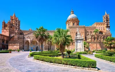 a large building with palm trees and a clock tower at Al Maqueda in Palermo