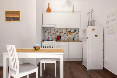 a white kitchen with a table and a refrigerator at Luce mediterranea a Monreale in Monreale
