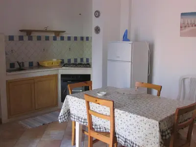 a kitchen with a table and a white refrigerator at il limone appartamenti 2 in San Vito lo Capo