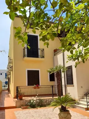 a building with black shuttered windows and plants at il limone appartamenti 2 in San Vito lo Capo