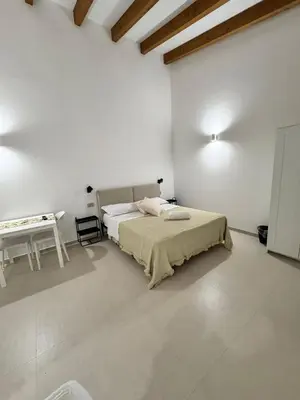 a white room with a bed and a table at Monolocale sotto la torre in San Vito lo Capo
