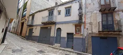 an old building with blue doors on a street at Beneath the Castle in Corleone