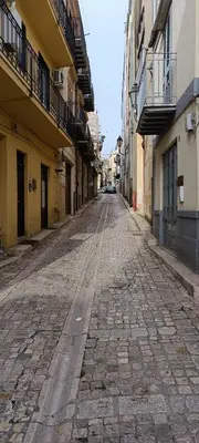 an empty street in an alley between buildings at Beneath the Castle in Corleone