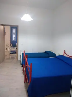 a bedroom with blue beds and a table and a chair at Casa Ferdinando e Maria in Palermo
