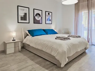 a white bedroom with a large bed with blue pillows at Casa Belsito in Palermo