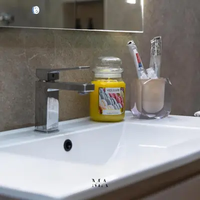 a bathroom sink with a jar of honey and a mirror at MEA Suite in Palermo