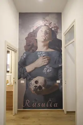 a mural of a woman holding a skull on a wall at Leoni di Sicilia in Palermo