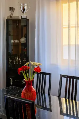 a red vase with red flowers sitting on a table at Villa Yasmine in Cinisi