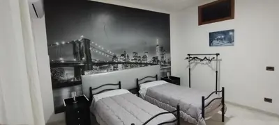 a bedroom with two beds and a mural of a city at Casa Emma 121 in Partinico