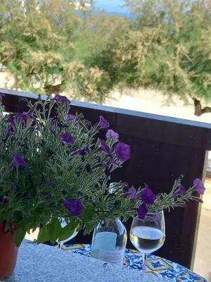 a table with a vase of purple flowers and a glass of wine at GiRosa House in Bagheria