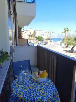 a table with a bowl of fruit and wine glasses on a balcony at GiRosa House in Bagheria