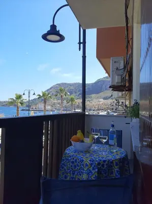 a table with a bowl of fruit on a balcony at GiRosa House in Bagheria