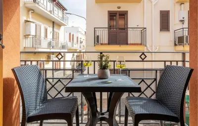 a table on a balcony with two chairs and wine glasses at 1 Bedroom Cozy Apartment In Balestrate in Balestrate