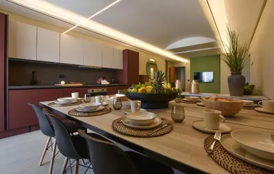 a long wooden table with chairs and a kitchen at 5 Bedroom Stunning Apartment In Trappeto in Trappeto