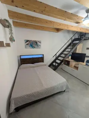a bedroom with a bed and a staircase at Central apartment with charm for 1 or 2 people - Casa Vacanze Luna in Lascari