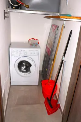 a laundry room with a washing machine and a red bucket at Central apartment with charm for 1 or 2 people - Casa Vacanze Luna in Lascari