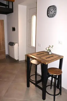 a table with two stools and a clock on a wall at Central apartment with charm for 1 or 2 people - Casa Vacanze Luna in Lascari