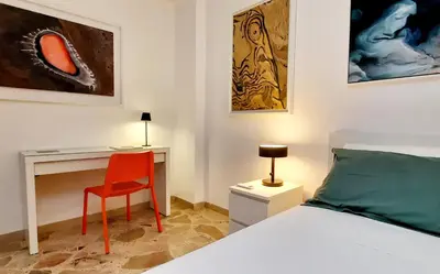 a bedroom with a bed and a desk with a red chair at Casa d'artista Max Serradifalco in Palermo