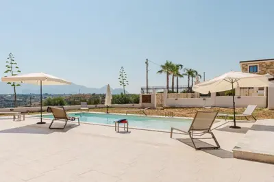 a swimming pool with two chairs and umbrellas at Villa con Piscina in Balestrate