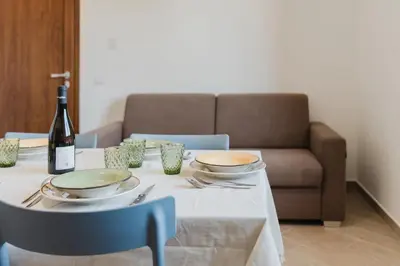 a white table with a bottle of wine and a table with chairs at Villa con Piscina in Balestrate
