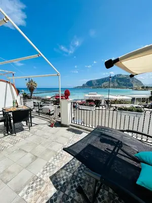 a patio with a table and a view of the ocean at beach front bliss mondello in Palermo