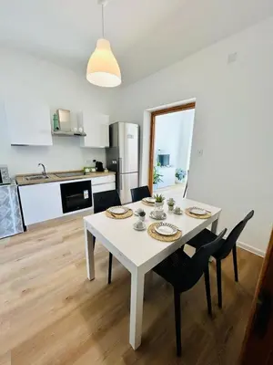 a white dining room table with chairs and a kitchen at beach front bliss mondello in Palermo