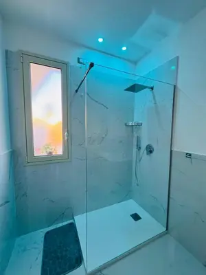 a bathroom with a glass shower with a window at From Flori in Terrasini