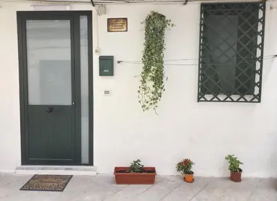 a black door and plants on a white wall at La casetta di John in Palermo