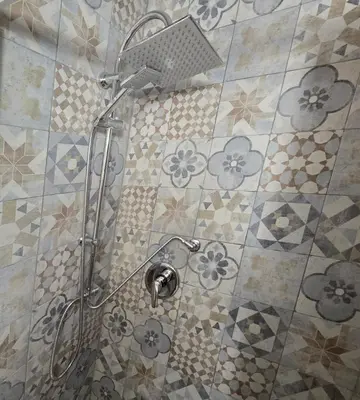 a shower in a bathroom with flowers on the tiles at La casetta di John in Palermo