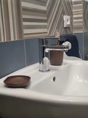 a bathroom sink with a faucet and a cup on it at La loggia Apartment in Palermo