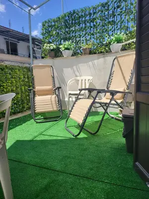 a patio with two chairs and a table on grass at La loggia Apartment in Palermo