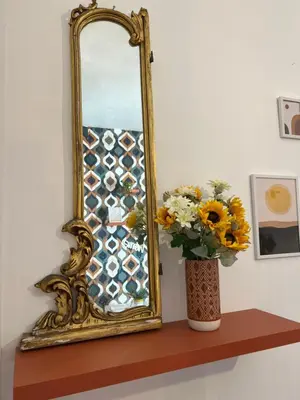 a mirror sitting on a shelf next to a vase with flowers at Casamori 3- nel cuore del mercato Ballarò in Palermo