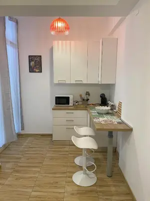a kitchen with white cabinets and a table and stool at La Casa di Baloo in Palermo