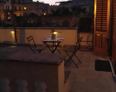 a table and chairs on a balcony at night at Villetta Casaurro in Bagheria