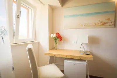 a small room with a desk and a vase of flowers at Casale La Macina - Hotel, Scopello in Scopello