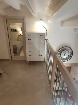 a hallway with a staircase with a clock and a dresser at Central modern vacation home in Lascari - Casa Vacanze Luna in Lascari