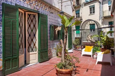 a building with green doors and plants on a patio at iFlat Suite del Barone with Terrace in Palermo