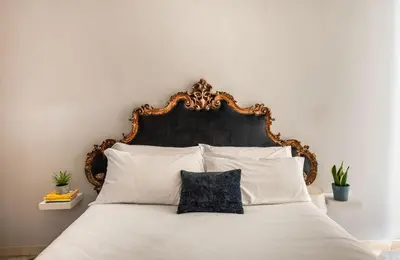 a bed with a black headboard and white pillows at iFlat Suite del Barone with Terrace in Palermo