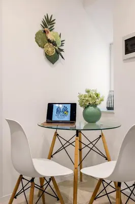 a table with a laptop and two white chairs at Vittorio Maison - centro storico in Palermo