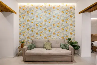 a couch in a living room with a floral wall at Vittorio Maison - centro storico in Palermo
