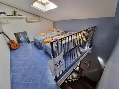 a room with two beds and a staircase with a guitar at Respiro di Mare by Holiday World in Buonfornello