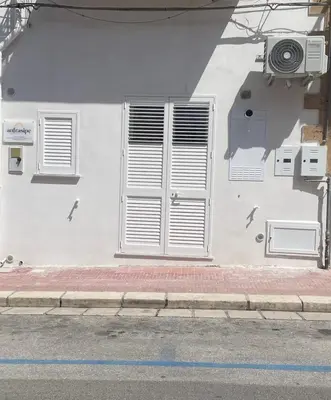 a white building with white shutters on the side of a street at Anfrasipe apartment in Terrasini
