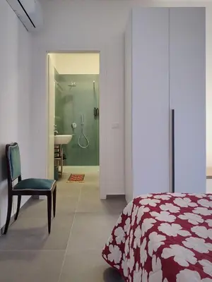 a bedroom with a bed and a chair and a bathroom at Cà Porto-Rooms with Balcony&Terrace in Santa Flavia