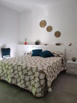 a bedroom with a bed with a comforter on it at Cà Porto-Rooms with Balcony&Terrace in Santa Flavia