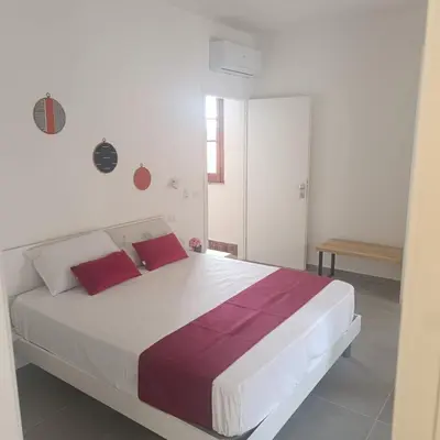 a white bedroom with a large bed with red pillows at Cà Porto-Rooms with Balcony&Terrace in Santa Flavia